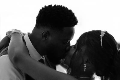 Un couple échange ses vœux de mariage dans une salle ornée de fresques et d'un lustre imposant.