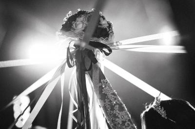 Un couple échange ses vœux de mariage dans une salle ornée de fresques et d'un lustre imposant.