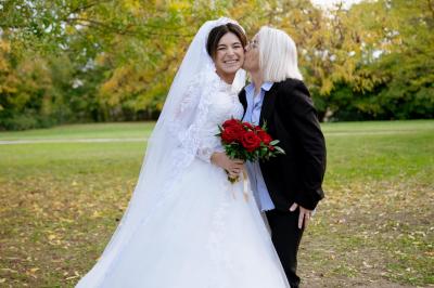 Un couple échange ses vœux de mariage dans une salle ornée de fresques et d'un lustre imposant.