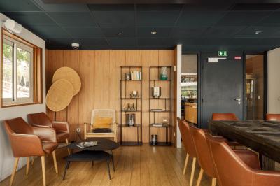 Salle de restaurant lumineuse avec des tables dressées, des chaises modernes et vue sur une rivière bordée de bâtiments.