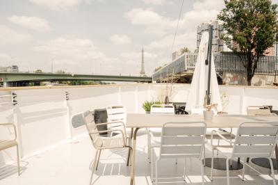 Salle de restaurant lumineuse avec des tables dressées, des chaises modernes et vue sur une rivière bordée de bâtiments.