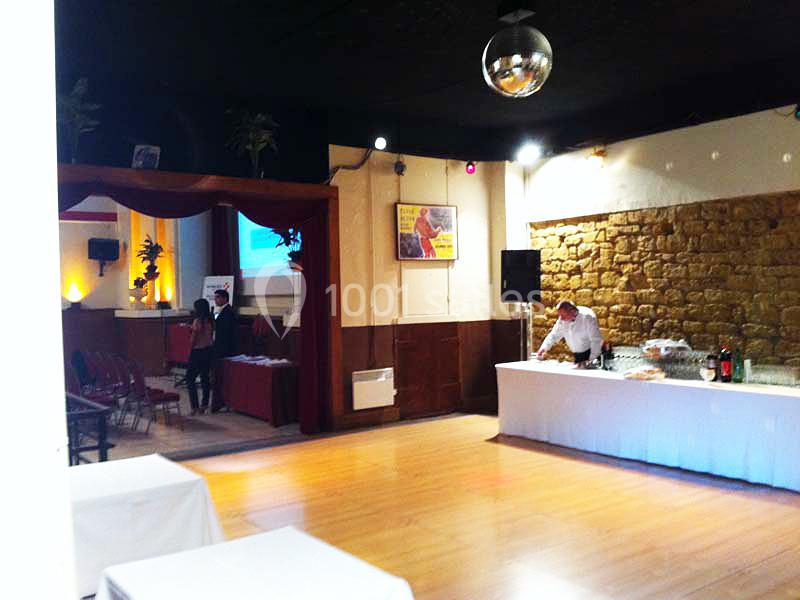 Salle de réception avec parquet, tables dressées, buffet, éclairage tamisé et une boule à facettes au plafond.