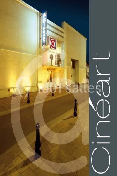 Façade éclairée d'un cinéma moderne avec enseigne ’Cinéart’ et entrée vitrée, vue de nuit.