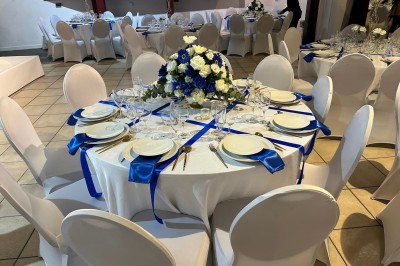 Miniature Location salle Nanterre (Hauts-de-Seine) - Le Cinéart #3 Table décorée pour un mariage avec chaises blanches, nappe bleue, fleurs blanches et éléments dorés sur une estrade.