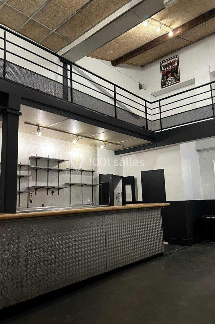 Intérieur d'un espace industriel avec un comptoir métallique, une mezzanine et des étagères murales.