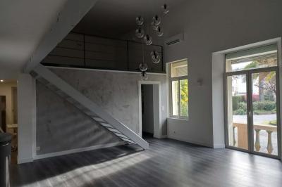 Salle lumineuse avec une grande table dressée pour un repas, décorée de fleurs blanches et rouges, entourée de chaises…