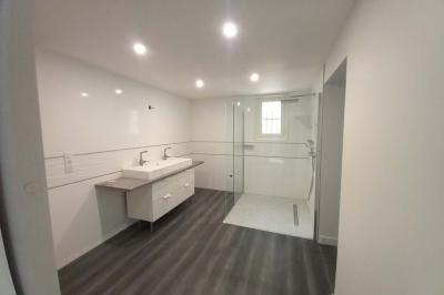 Salle lumineuse avec une grande table dressée pour un repas, décorée de fleurs blanches et rouges, entourée de chaises…