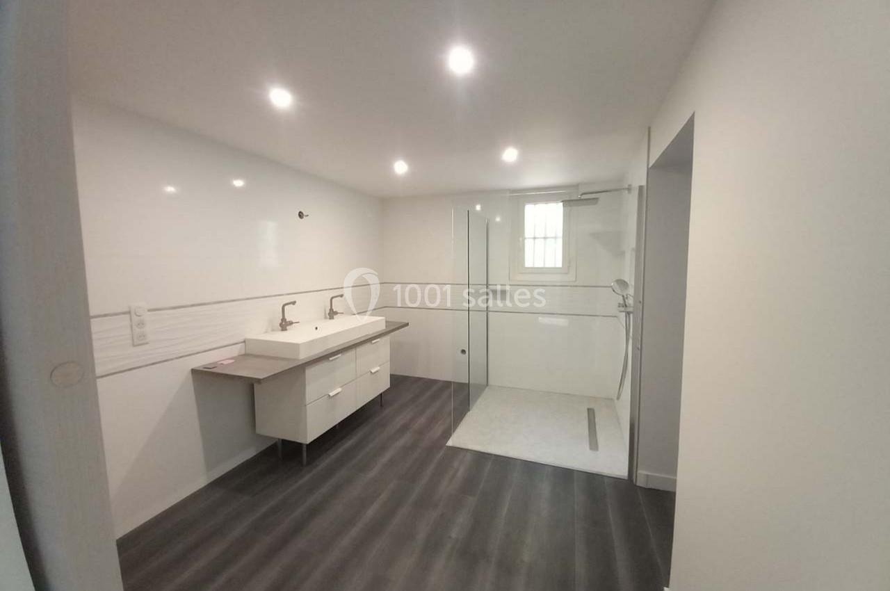 Salle de bain moderne avec douche à l'italienne, double vasque et sol en revêtement effet bois sombre.