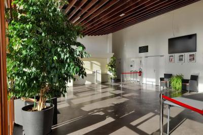 Miniature Hall Accueil lumineux avec comptoir blanc, porte vitrée à gauche laissant entrer la lumière et plante verte à droite.