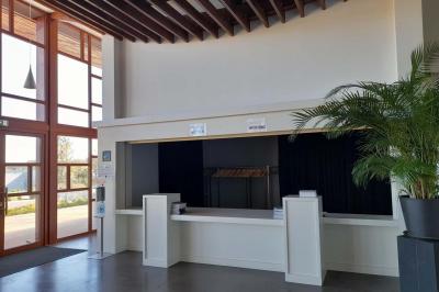 Miniature Vestiaire Accueil lumineux avec comptoir blanc, porte vitrée à gauche laissant entrer la lumière et plante verte à droite.