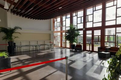 Miniature Hall Accueil avec comptoir blanc, porte-manteaux en arrière-plan, grande baie vitrée et plante verte à droite.