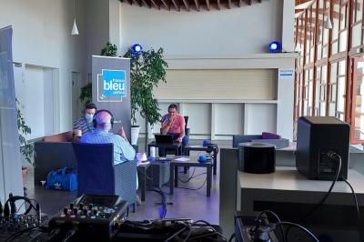 Miniature Hall Accueil avec comptoir blanc, porte-manteaux en arrière-plan, grande baie vitrée et plante verte à droite.