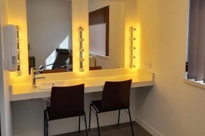 Miniature Loge Accueil avec comptoir blanc, porte-manteaux en arrière-plan, grande baie vitrée et plante verte à droite.