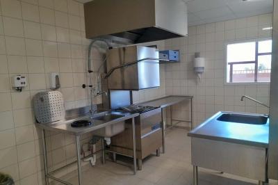 Miniature Office traiteur Accueil avec comptoir blanc, porte-manteaux en arrière-plan, grande baie vitrée et plante verte à droite.