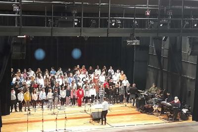 Miniature Répétition chorale Accueil avec comptoir blanc, porte-manteaux en arrière-plan, grande baie vitrée et plante verte à droite.