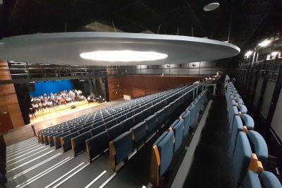 Miniature Répétition chorale Accueil avec comptoir blanc, porte-manteaux en arrière-plan, grande baie vitrée et plante verte à droite.