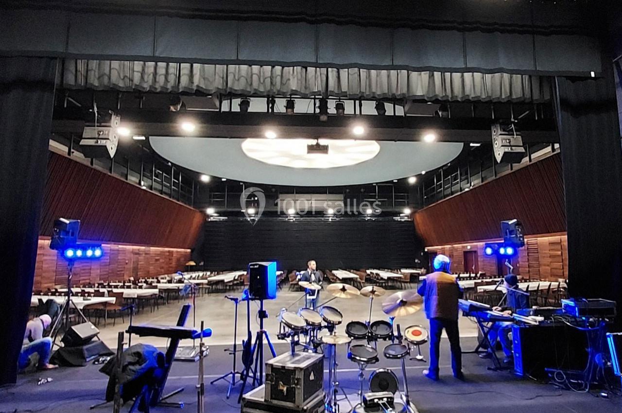 Salle de spectacle avec instruments de musique sur scène, techniciens ajustant l'éclairage et le son.