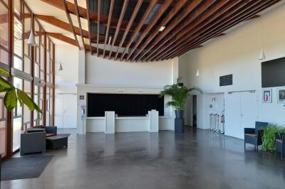 Miniature Vestiaire Accueil avec comptoir blanc, porte-manteaux en arrière-plan, grande baie vitrée et plante verte à droite.