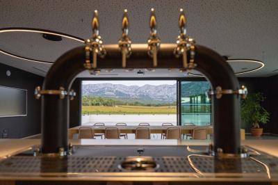 Des personnes assises à une table en extérieur, discutant et partageant un repas devant un paysage de vignobles au coucher…