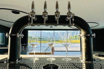 Des personnes assises à une table en extérieur, discutant et partageant un repas devant un paysage de vignobles au coucher…