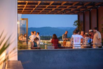 Des personnes assises à une table en extérieur, discutant et partageant un repas devant un paysage de vignobles au coucher…