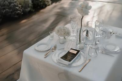 Table en bois longue dressée en extérieur, ornée de fleurs, citrons et vaisselle, entourée d'arbres et de verdure.