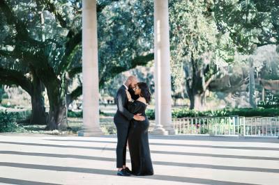 Table en bois longue dressée en extérieur, ornée de fleurs, citrons et vaisselle, entourée d'arbres et de verdure.
