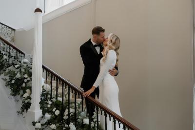 Table en bois longue dressée en extérieur, ornée de fleurs, citrons et vaisselle, entourée d'arbres et de verdure.
