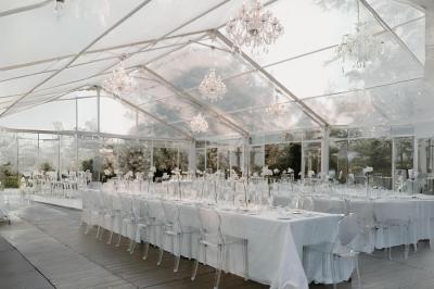 Table en bois longue dressée en extérieur, ornée de fleurs, citrons et vaisselle, entourée d'arbres et de verdure.