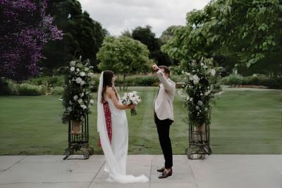 Table en bois longue dressée en extérieur, ornée de fleurs, citrons et vaisselle, entourée d'arbres et de verdure.
