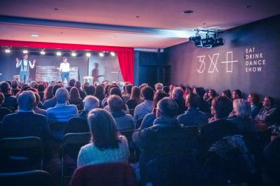 Miniature Troyes la Champagne Events #12 Femme de dos dans une chambre mansardée avec poutres apparentes, lit, télévision et baignoire en arrière-plan.