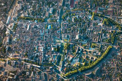 Miniature Troyes la Champagne Events #2 Femme de dos dans une chambre mansardée avec poutres apparentes, lit, télévision et baignoire en arrière-plan.