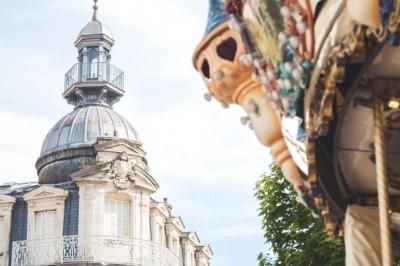 Miniature Troyes la Champagne Events #4 Femme de dos dans une chambre mansardée avec poutres apparentes, lit, télévision et baignoire en arrière-plan.