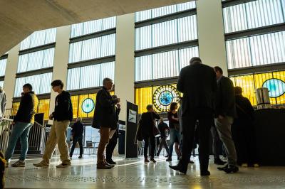 Miniature Troyes la Champagne Events #6 Femme de dos dans une chambre mansardée avec poutres apparentes, lit, télévision et baignoire en arrière-plan.