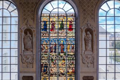 Miniature Troyes la Champagne Events #11 Femme de dos dans une chambre mansardée avec poutres apparentes, lit, télévision et baignoire en arrière-plan.
