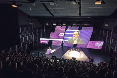 Miniature Troyes la Champagne Events #5 Femme de dos dans une chambre mansardée avec poutres apparentes, lit, télévision et baignoire en arrière-plan.