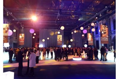 Miniature Troyes la Champagne Events #9 Femme de dos dans une chambre mansardée avec poutres apparentes, lit, télévision et baignoire en arrière-plan.