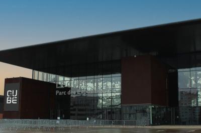 Miniature Troyes la Champagne Events #8 Femme de dos dans une chambre mansardée avec poutres apparentes, lit, télévision et baignoire en arrière-plan.