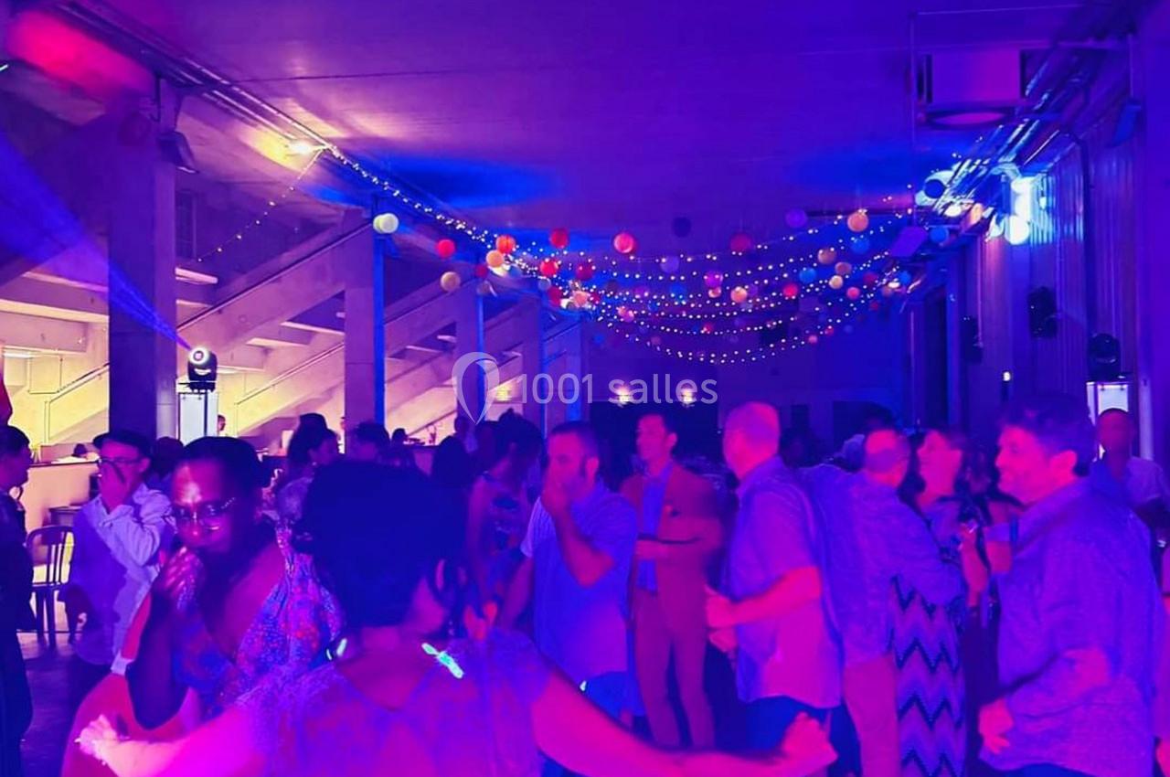 Personnes dansant sous des guirlandes lumineuses et des lanternes colorées dans une salle éclairée par des lumières…