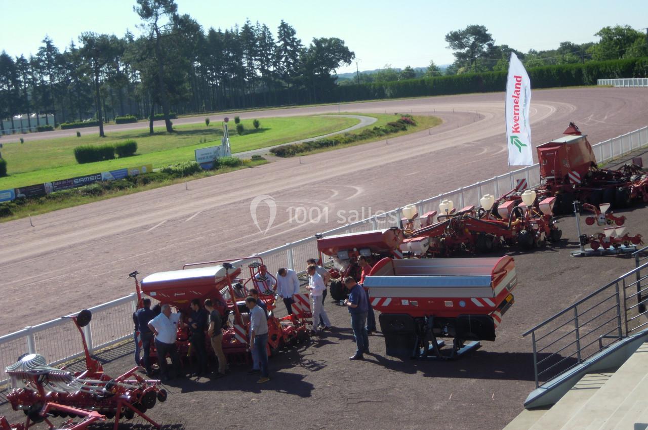 Vue d'une exposition de machines agricoles en plein air, avec des visiteurs observant les équipements exposés.