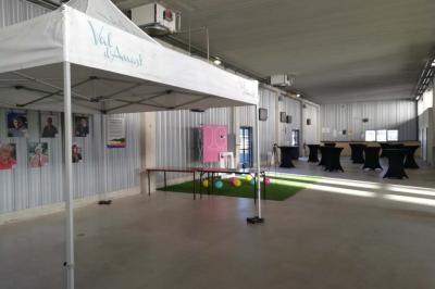 Un motocycliste effectue un saut spectaculaire au-dessus de véhicules dans un espace extérieur ensoleillé.