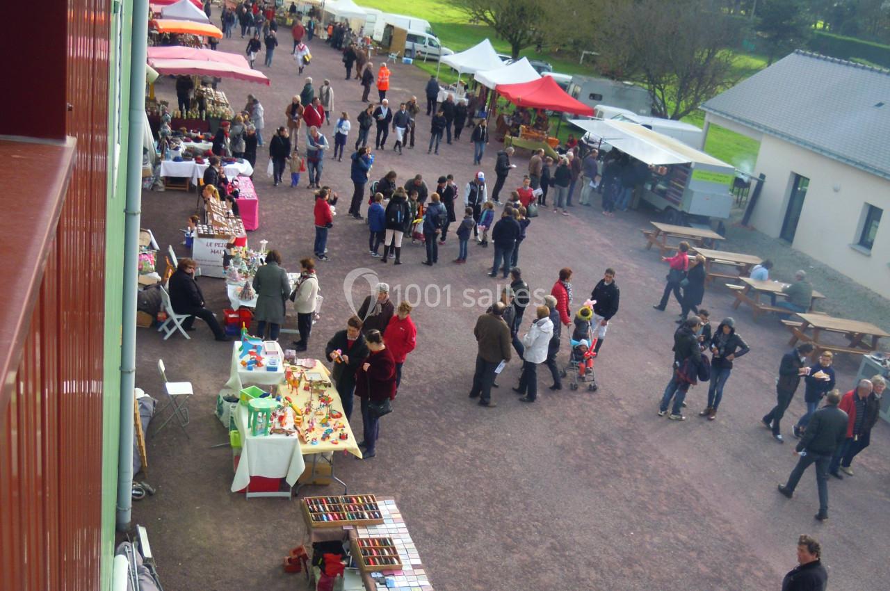 Vue aérienne d'un marché en plein air avec des stands colorés et des visiteurs se déplaçant entre les étals.