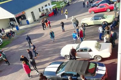 Un motocycliste effectue un saut spectaculaire au-dessus de véhicules dans un espace extérieur ensoleillé.