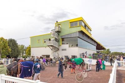 Un motocycliste effectue un saut spectaculaire au-dessus de véhicules dans un espace extérieur ensoleillé.