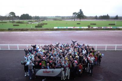 Un motocycliste effectue un saut spectaculaire au-dessus de véhicules dans un espace extérieur ensoleillé.