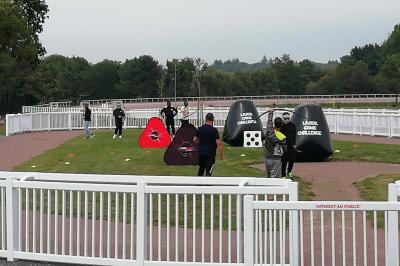 Un motocycliste effectue un saut spectaculaire au-dessus de véhicules dans un espace extérieur ensoleillé.