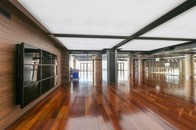 Salle de conférence lumineuse avec des rangées de chaises en bois, deux écrans et de grandes fenêtres donnant sur l…