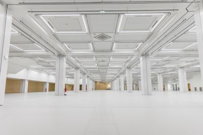 Salle de conférence lumineuse avec des rangées de chaises en bois, deux écrans et de grandes fenêtres donnant sur l…