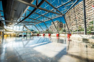 Salle de conférence lumineuse avec des rangées de chaises en bois, deux écrans et de grandes fenêtres donnant sur l…