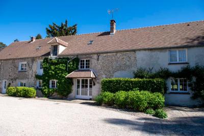 Table en bois clair avec un livre, une carte et un vase contenant une fleur verte, près d'un fauteuil blanc.